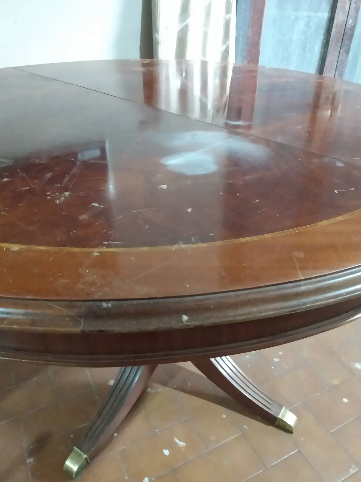 Mesa redonda antes de la restauración, con la madera opaca y rayada.